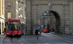 Mit Peter unterwegs in Bern -     Combino Tram 654 fhrt nach der Durchfahrt des Kfigturms in einen lteren Teil der Altstadt ein, whrend ein Trolleybus der Linie 12 den Turm in