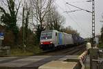186 284 legt sich am 11.12.24 mit einem Containerzug auf dem Weg nach Krefeld am Bahnbergang Viehgasse in Meerbusch in die Kurve.