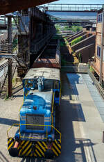 Die Dieselhydraulische Normalspur-Lokomotive Nr. 34, eine Henschel DHG 240 B  Esslinger , der Völklinger Hütte (ehem. Röchling'schen Eisen- und Stahlwerke GmbH in Völklingen/Saar, ab 1982 ARBED-Saarstahl GmbH, ab 1986 Saarstahl Völklingen GmbH) hier am 01 Juli 2025 abgestellt als Denkmal, mit zwei selbstentladende Schüttgutwagen der Gattung Fad oder Falns am Eingang der Rohstoffentladebunker in Richtung Hüttenbahnhof. Die Darstellung steht für den Rohstofftransport der Hütte zur Herstellung des Sintergutes. Die Lok war auch auf Bundesbahn Gleisen zugelassen. Heutiger Eigentümer der Lok und Wagen ist die Initiative Völklinger Hütte e.V..

Die zweiachsige dieselhydraulische Lok mit Antrieb über Gelenkwellen wurde 1969 von Henschel in Kassel unter der Fabriknummer 31210 gebaut und an die Röchling'sche Eisen- und Stahlwerke GmbH in Völklingen als Lok 34 geliefert. Weiterer Lebenslauf/Umfirmierungen: 
01.01.1971 > Stahlwerke Röchling-Burbach GmbH, Völklingen  34  
Juni 1982 	 > ARBED-Saarstahl GmbH, Völklingen  34  
Juni 1986 	 > Saarstahl Völklingen GmbH, Völklingen  34  
10.05.1989 > Saarstahl AG, Völklingen  34  
Später an MGS - Metallurgische Gesellschaft Saar mbH, Völklingen  34  
März 1999 	an Weltkulturerbe Völklinger Hütte - Europäisches Zentrum für Kunst und Industriekultur GmbH, Völklingen und Aufstellung als Denkmal. 

Die Lokomotive war bis zu einem Motorschaden 1997 in verschiedenen Bereichen eingesetzt: Transport von Duplexeisen zwischen der Mischerhalle und dem Siemens-Martin-Werk, im Bereich des Siemens-Martin-Werks, der Elektroöfen und des Hammerwerks sowie nach Einbau einer Funkfernsteuerung im Hafenbereich der Saarstahl AG.