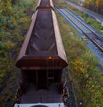 Blick von oben auf den, nun leeren, vierachsigen offenen Drehgestell-Schüttgutwagen mit dosierbarer Schwerkraftentladung, 31 80 6940 387 D-DB, Gattung Facs 124 (ex DR Gattung Eads-y), der DB Cargo AG, steht 12 Oktober 2025, eingereiht in einen Schotterzug hier direkt hinter der Lok, im Bahnhof Herdorf. Gut sieht man hier die vier Kammern/Trichter. 