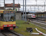 Die Strassenbahn 'Be 4/8 003' alias 94 800 450 003-9 D-TVYS wartet in Chavornay auf die Fahrgäste der S-Bahnen während auf der Jurasüdfusslinie noch die ICN RABDe 500 015 'Jean-Jacques Rousseau' und RABDe 500 029 'Eduard Spelterini' vo ...